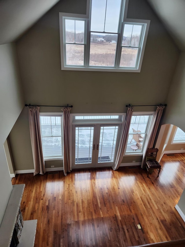 unfurnished living room with high vaulted ceiling, french doors, and hardwood / wood-style flooring