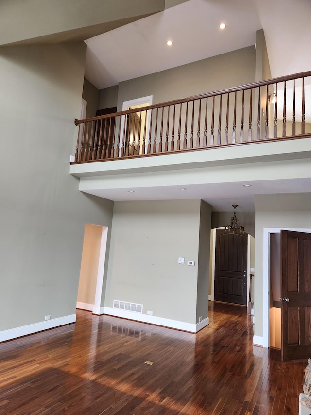 unfurnished living room featuring visible vents, baseboards, a towering ceiling, wood-type flooring, and recessed lighting