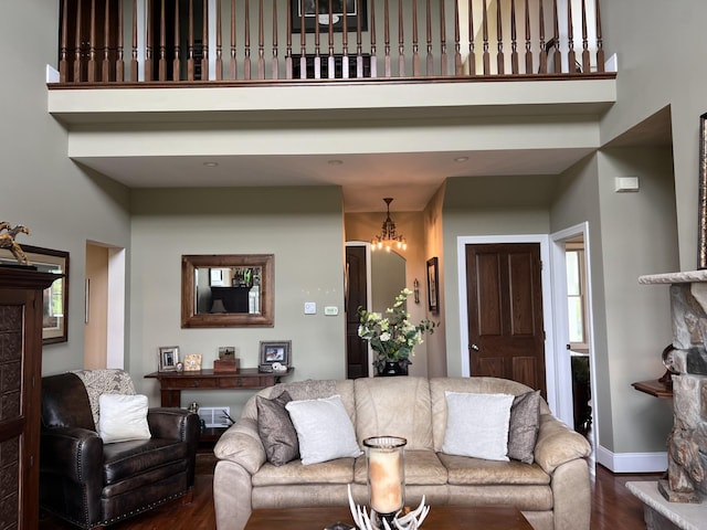 living room featuring a chandelier, a high ceiling, wood finished floors, and baseboards