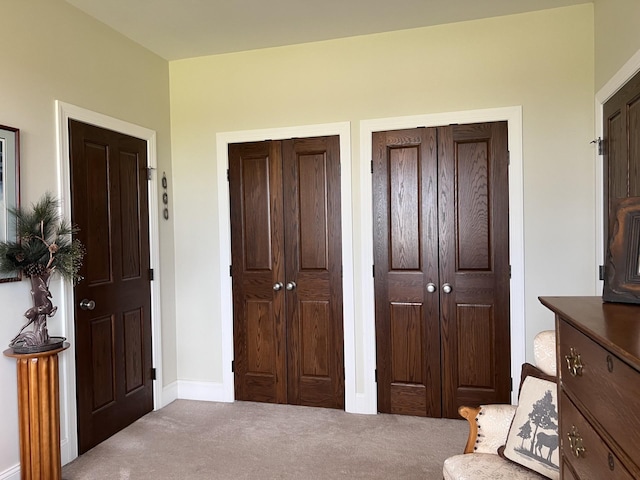 carpeted bedroom featuring baseboards and multiple closets