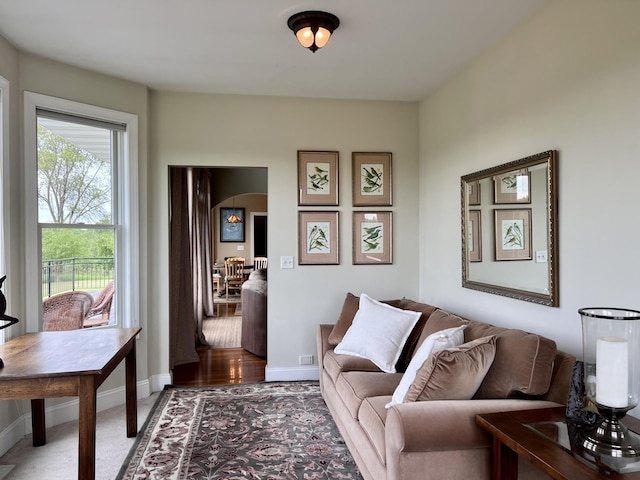 living area with baseboards and arched walkways