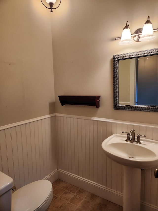 bathroom featuring a wainscoted wall and toilet