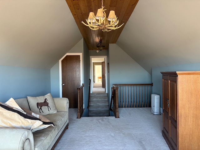 interior space with carpet floors, a notable chandelier, vaulted ceiling, an upstairs landing, and wooden ceiling