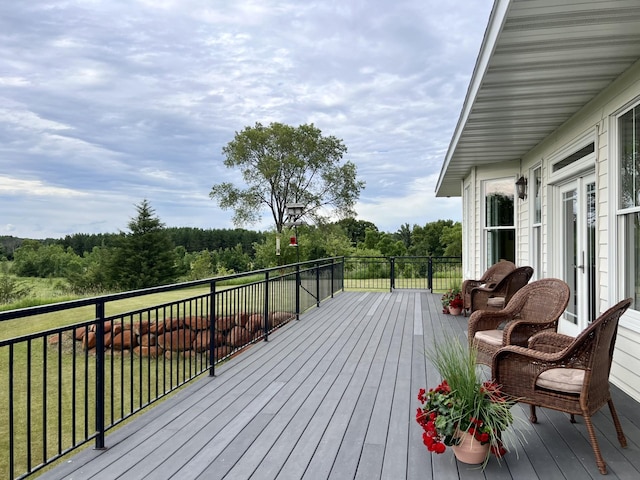 deck featuring a yard, a forest view, and french doors