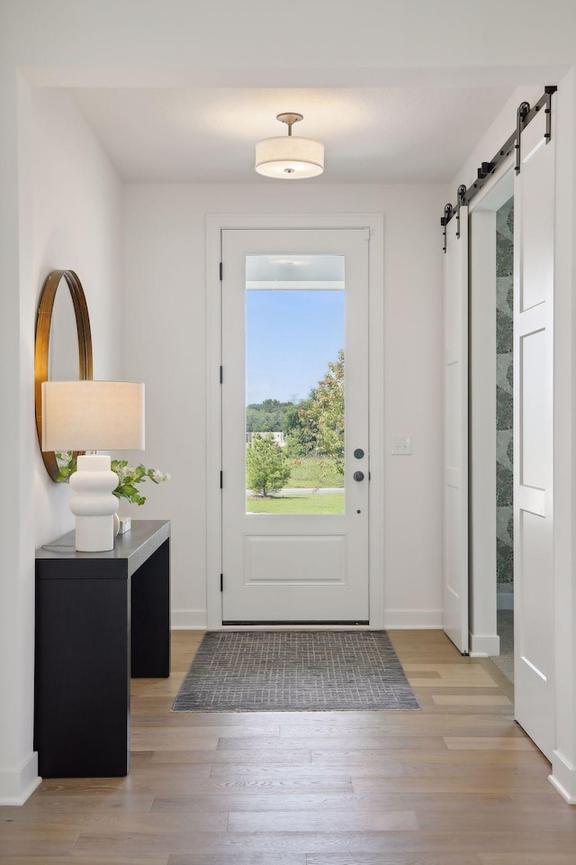 doorway to outside with a barn door and light wood-type flooring