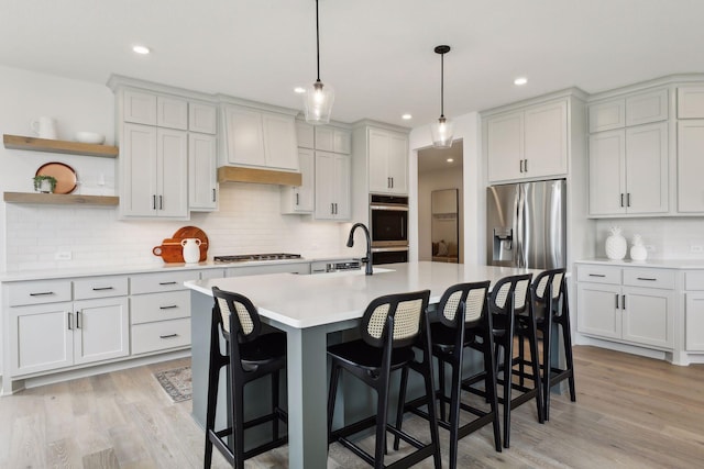 kitchen featuring backsplash, pendant lighting, a breakfast bar, light wood-type flooring, and stainless steel appliances