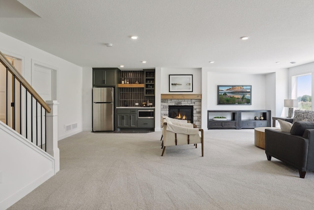 carpeted living room featuring a textured ceiling and a fireplace