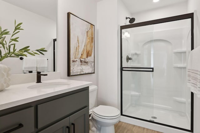 bathroom with an enclosed shower, vanity, toilet, and hardwood / wood-style floors