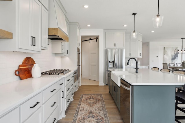 kitchen with hanging light fixtures, a barn door, a breakfast bar, and white cabinetry