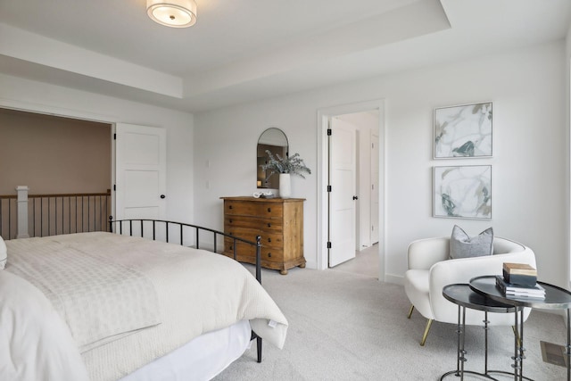 bedroom featuring light colored carpet and a raised ceiling