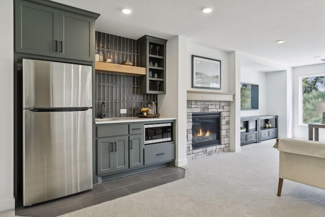 bar with stainless steel appliances, a stone fireplace, tasteful backsplash, sink, and gray cabinetry