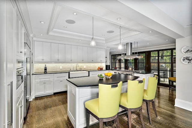 kitchen featuring sink, a kitchen island, island exhaust hood, white cabinets, and a kitchen bar