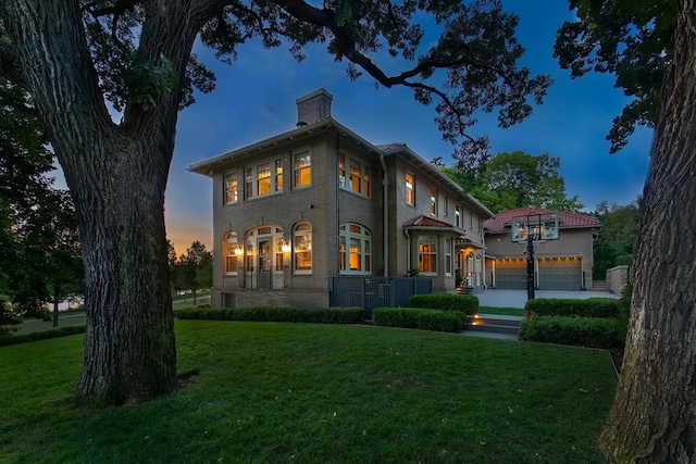 back house at dusk featuring a yard and a garage