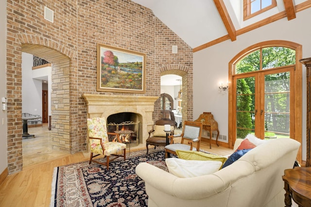 living room with french doors, high vaulted ceiling, hardwood / wood-style flooring, and a premium fireplace