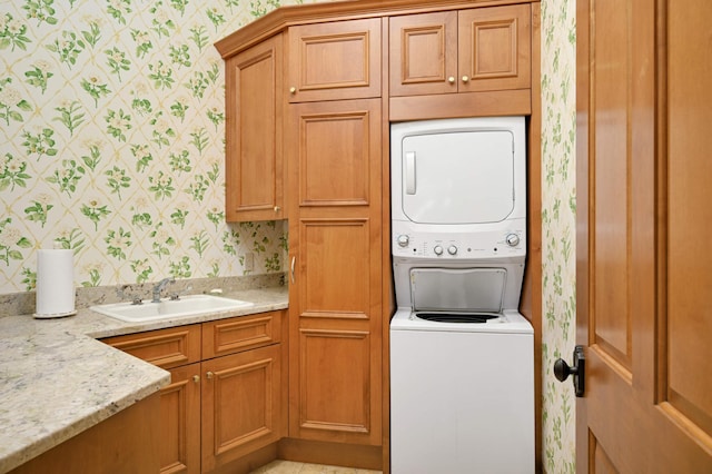 laundry area with sink, stacked washing maching and dryer, and cabinets