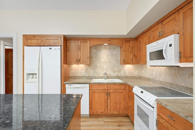 kitchen featuring backsplash, white appliances, stone countertops, light hardwood / wood-style floors, and sink