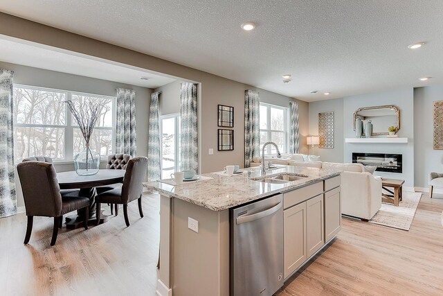 kitchen featuring light hardwood / wood-style flooring, dishwasher, a healthy amount of sunlight, and an island with sink