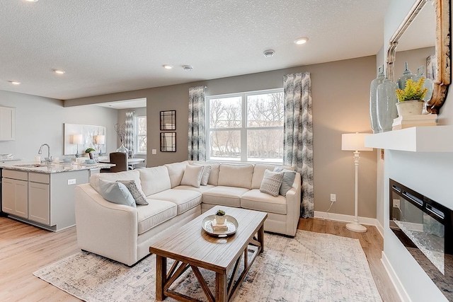 living room featuring sink, a textured ceiling, and light hardwood / wood-style flooring