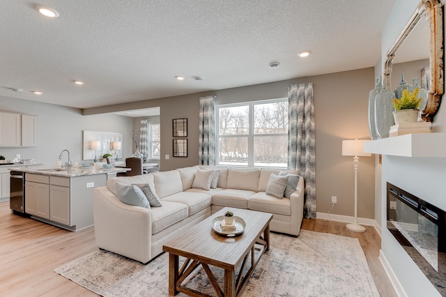 living room with light hardwood / wood-style floors, a textured ceiling, and sink