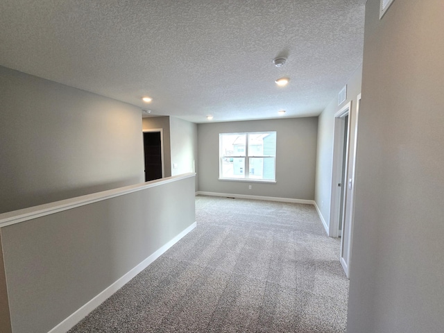 carpeted spare room with a textured ceiling