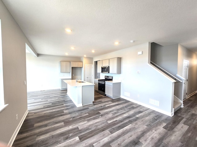 kitchen featuring a center island with sink, appliances with stainless steel finishes, dark hardwood / wood-style floors, gray cabinetry, and sink