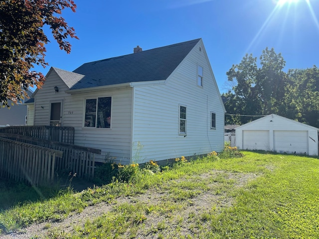 rear view of house featuring an outbuilding, a yard, and a garage