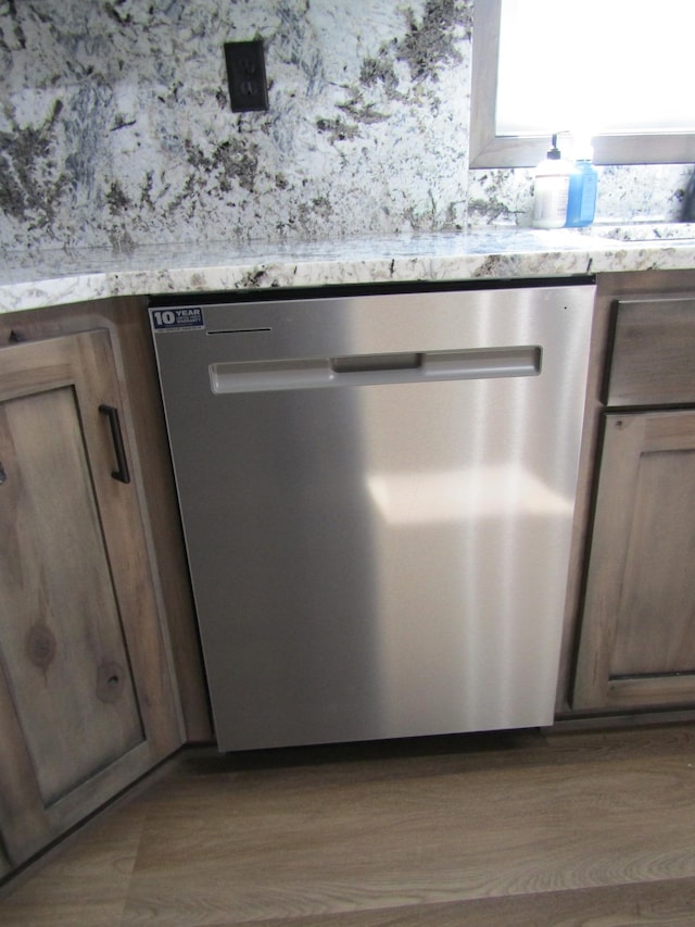 interior details with stainless steel dishwasher and light hardwood / wood-style flooring