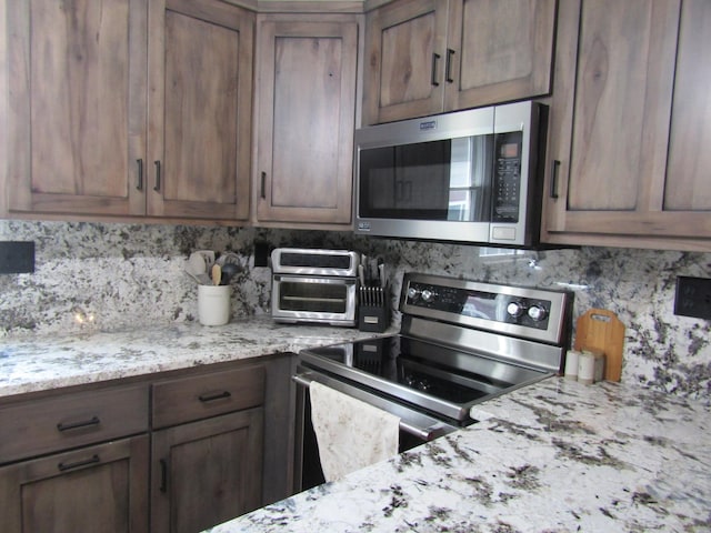 kitchen featuring light stone counters, stainless steel appliances, and decorative backsplash