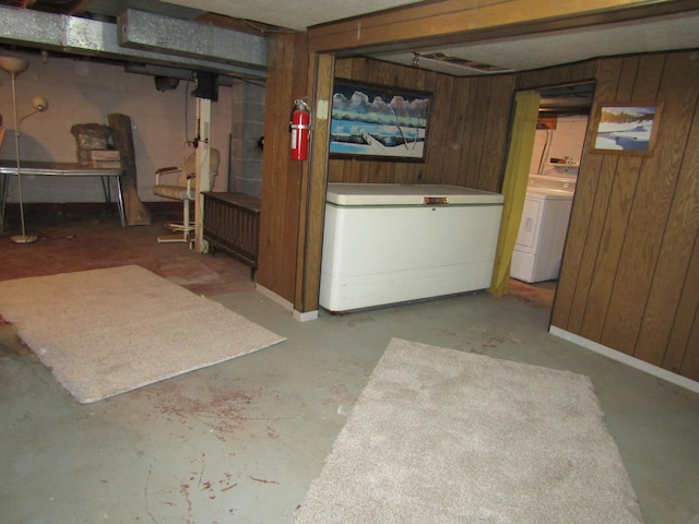 basement with white fridge, wood walls, and washer / clothes dryer