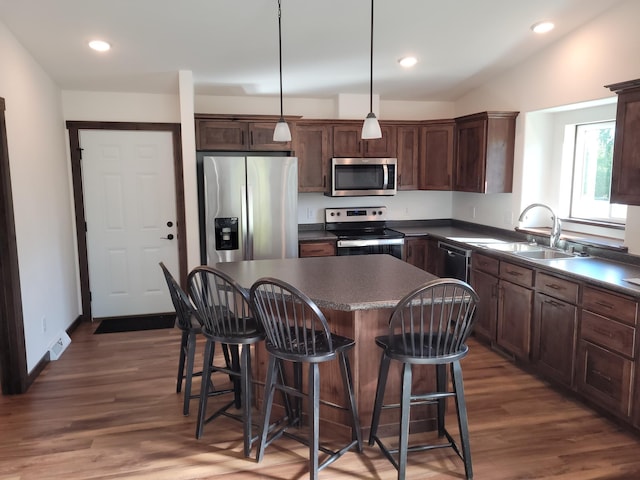 kitchen featuring stainless steel appliances, dark hardwood / wood-style flooring, sink, a kitchen island, and pendant lighting