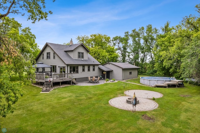 back of property with a yard, a patio area, an outdoor fire pit, and a pool side deck