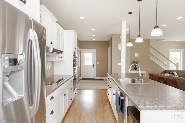 16305 57th St SE, Kindred, ND 58051 - kitchen featuring stainless steel appliances, a sink, ventilation hood, white cabinetry, and an island with sink