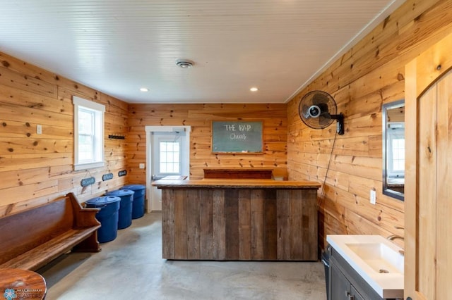 16305 57th St SE, Kindred, ND 58051 - kitchen featuring wood walls, finished concrete flooring, a sink, recessed lighting, and a peninsula