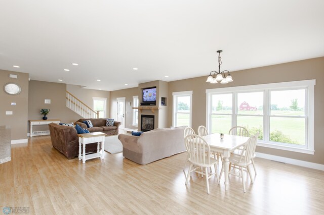 16305 57th St SE, Kindred, ND 58051 - living room featuring baseboards, light wood-style floors, a glass covered fireplace, stairway, and recessed lighting