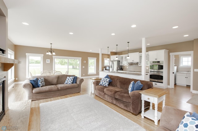 16305 57th St SE, Kindred, ND 58051 - living area featuring light wood finished floors, plenty of natural light, a chandelier, a glass covered fireplace, and recessed lighting