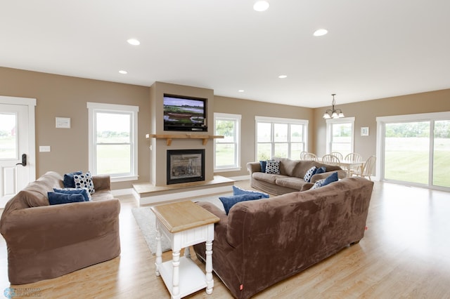 16305 57th St SE, Kindred, ND 58051 - living area featuring light wood finished floors, a chandelier, a glass covered fireplace, and recessed lighting