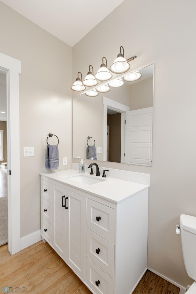 16305 57th St SE, Kindred, ND 58051 - half bathroom featuring wood finished floors, toilet, vanity, and baseboards