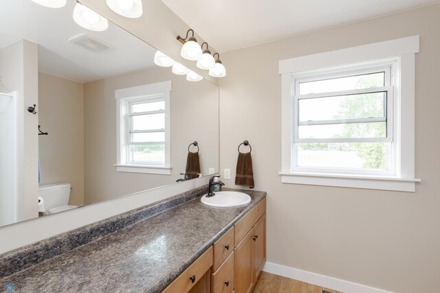 16305 57th St SE, Kindred, ND 58051 - bathroom with toilet, vanity, baseboards, and wood finished floors