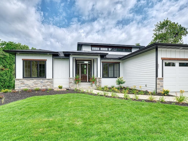 prairie-style house with a front lawn, stone siding, a garage, and board and batten siding