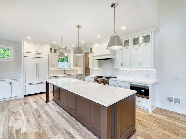 kitchen featuring a large island, white cabinets, sink, and built in appliances