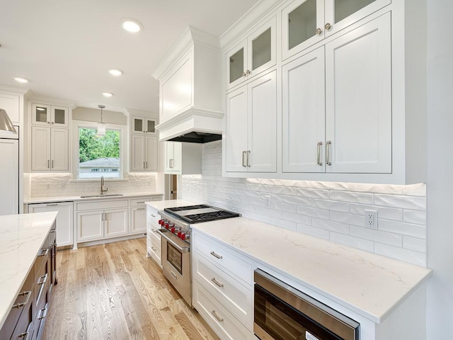 kitchen with white cabinetry, hanging light fixtures, stainless steel appliances, and sink