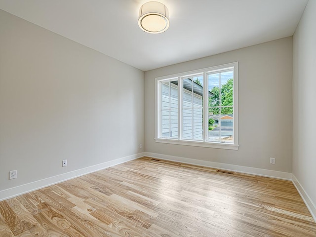 spare room with baseboards, light wood-type flooring, and visible vents