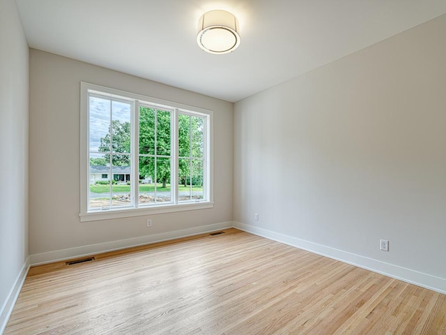 unfurnished room featuring a wealth of natural light, visible vents, and wood finished floors