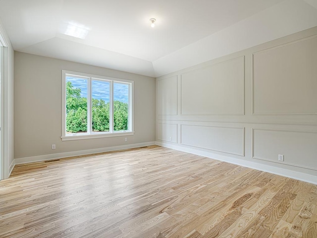 spare room featuring vaulted ceiling and light hardwood / wood-style floors