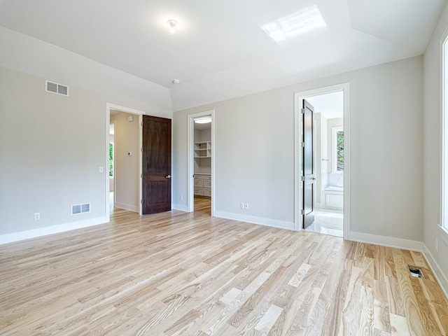 empty room with light wood-type flooring, visible vents, and baseboards
