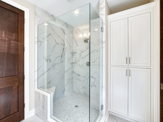 bathroom with an inviting chandelier, a marble finish shower, and marble finish floor