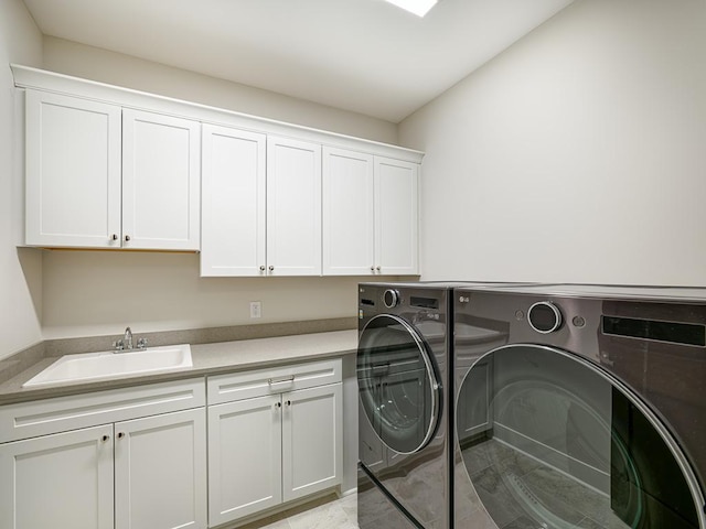 washroom featuring a sink, washing machine and dryer, and cabinet space