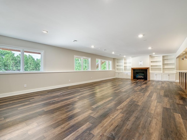 unfurnished living room with a fireplace, recessed lighting, baseboards, and dark wood finished floors
