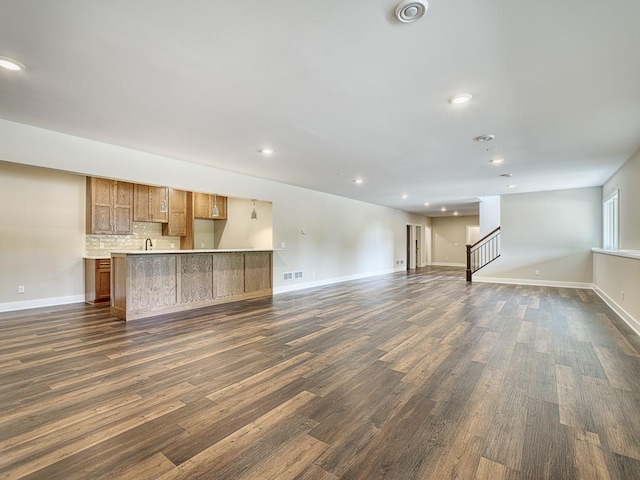 unfurnished living room featuring stairs, baseboards, visible vents, and dark wood finished floors
