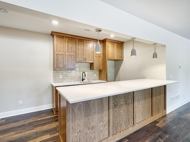 kitchen with a peninsula, baseboards, decorative light fixtures, tasteful backsplash, and dark wood-style floors